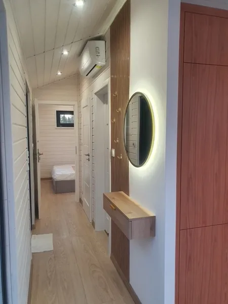 Langer Flur im skandinavischen Stil in einem winterfesten Bungalow der MONO-Serie von Compact Haus mit Garderobe, LED-Spiegel, Klimaanlage und Einbauschrank.