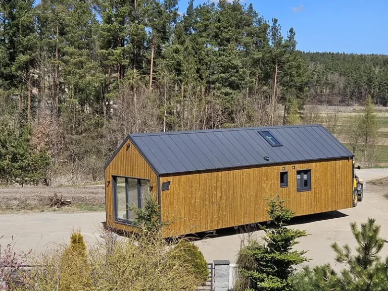 Schlüsselfertige Anlieferung eines winterfesten Ferienhauses der MONO-Serie von Compact Haus mit Holzfassade, Satteldach, Dachfenster und großer Glasfront.