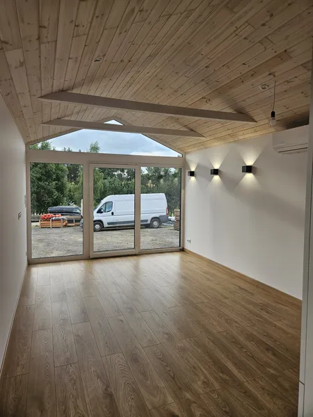 Großer Wohnraum im skandinavischen Stil in einem winterfesten Ferienhaus der MONO-Serie von Compact Haus mit bodentiefer Glasfront, Schiebetür und Klimaanlage.