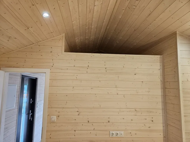 Gemütlicher Wohnbereich im skandinavischen Stil in einem Ferienhaus der MONO-Serie von Compact Haus mit Echtholzverkleidung, Galerie und offenem Raumkonzept.