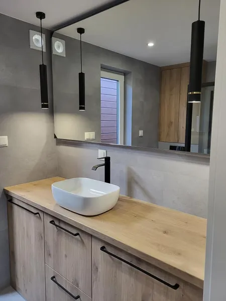 Eleganter Waschbereich in einem schlüsselfertigen Minihaus der MONO-Serie von Compact Haus mit Holzwaschtisch, Aufsatzbecken und Designer-Pendelleuchten.