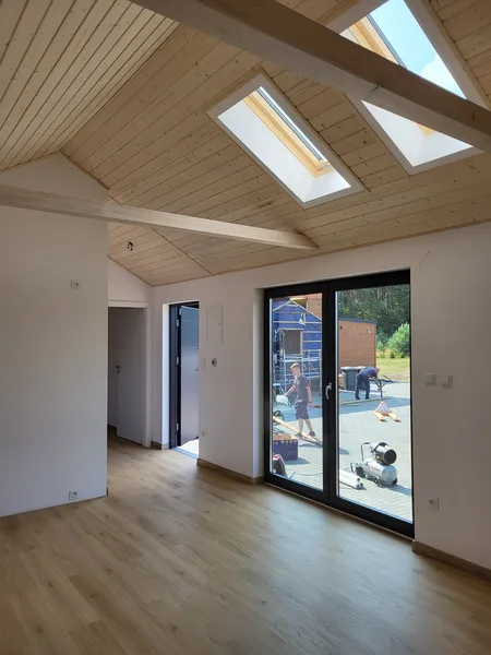 Lichtdurchfluteter Innenraum im skandinavischen Stil in einem Minihaus der MONO-Serie von Compact Haus mit Dachfenstern, sichtbaren Dachbalken und bodentiefer Fenstertür.