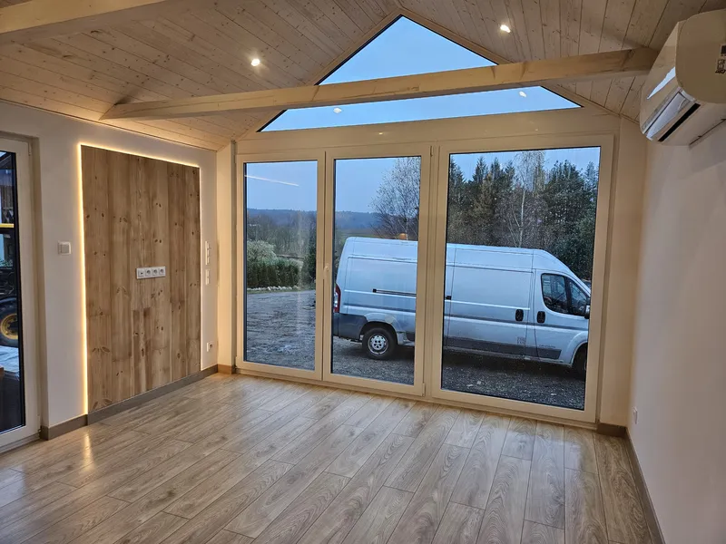 Großzügiger Wohnbereich im modernen Loft-Stil in einem Minihaus der MONO-Serie von Compact Haus mit bodentiefer Fensterfront, Giebelfenster und Klimaanlage.