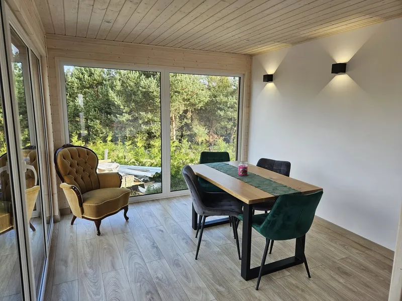 Lichtdurchfluteter Essbereich im modernen Loft-Stil in einem Minihaus der MONO-Serie von Compact Haus mit bodentiefen Fenstern, Echtholzdecke und gemütlicher Sitzecke.
