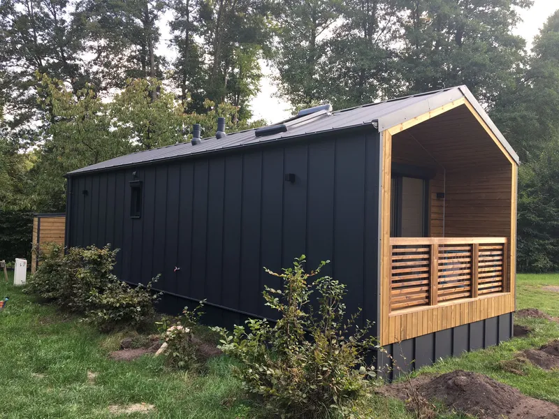 Modernes Mobilheim im Barnhouse-Stil von Compact Haus mit anthrazitfarbener Stehfalzblech-Fassade und integrierter Holzterrasse.