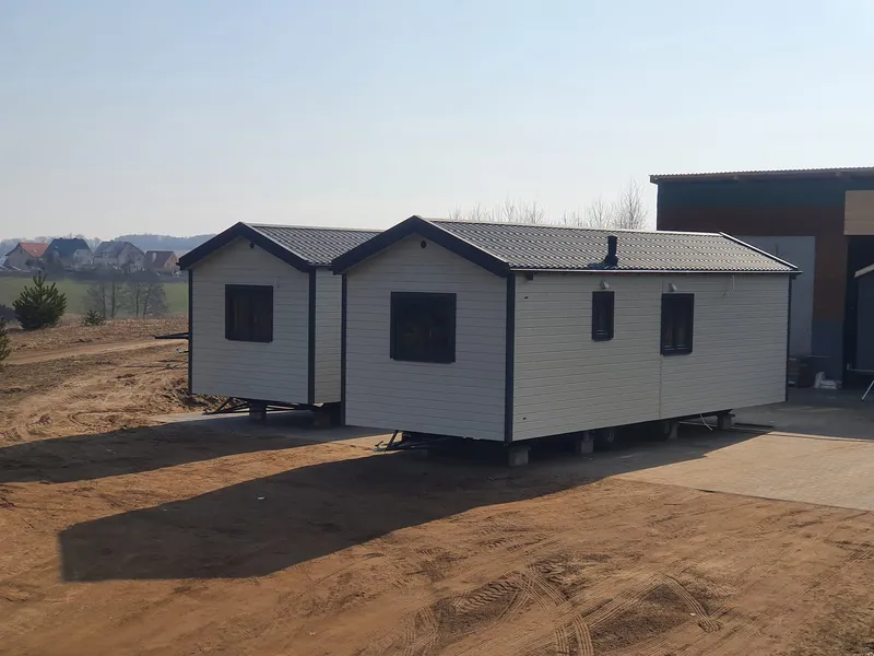 Zwei autarke Wohnmodule von Compact Haus auf separaten Trailer-Fahrgestellen mit Satteldach.