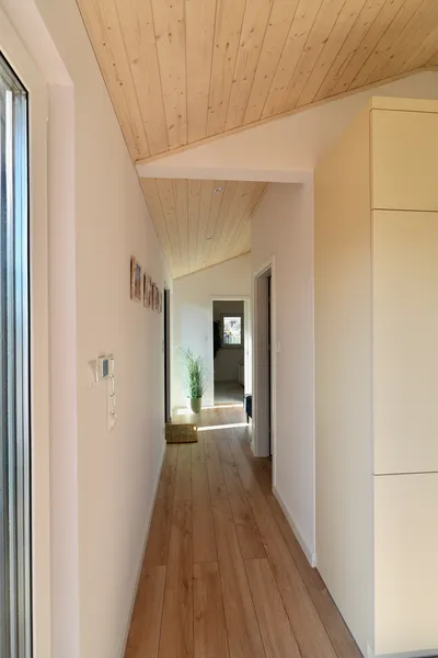 Langer, heller Flur in einem Compact Haus Mobilheim mit Blick durch das gesamte Haus, einer schrägen Holzdecke mit Spots und Einbauschränken.