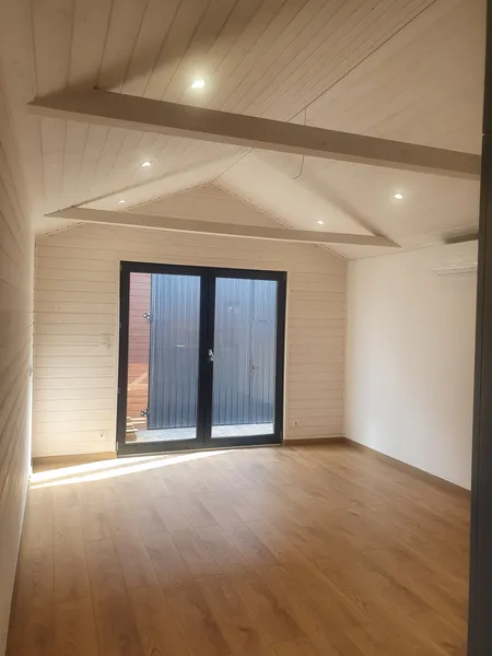 Heller Wohnraum im modernen skandinavischen Stil in einem Mobilheim der MONO-Serie von Compact Haus mit bodentiefer Fenstertür, Klimaanlage und Echtholzdecke.