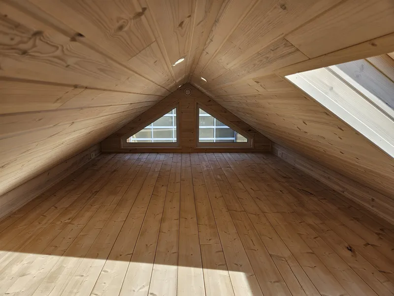 Gemütliche Schlafgalerie im Loft-Stil in einem winterfesten Mobilheim der MONO-Serie von Compact Haus mit Echtholzverkleidung, Giebelfenstern und Dachfenster.