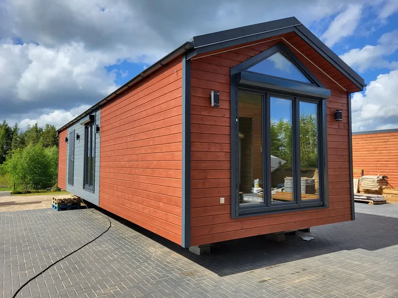 Modernes Mobilheim von Compact Haus mit großer Panorama-Glasfront, Giebeldach und hochwertiger Holzfassade.