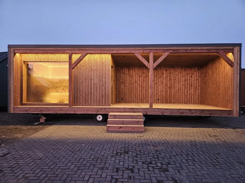 Luxuriöses, winterfestes Mobilheim der MONO-Serie von Compact Haus mit integrierter Sauna, großem Panoramafenster und einer überdachten Terrasse mit LED-Beleuchtung.