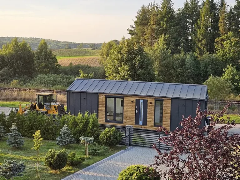 Modernes Mobilheim der MONO-Serie von Compact Haus mit Holzfassade und anthrazitfarbenen Fassadenelementen auf einem Grundstück.