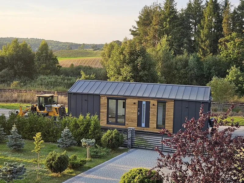 Modernes Mobilheim der MONO-Serie von Compact Haus mit Holzfassade und anthrazitfarbenen Fassadenelementen auf einem Grundstück.