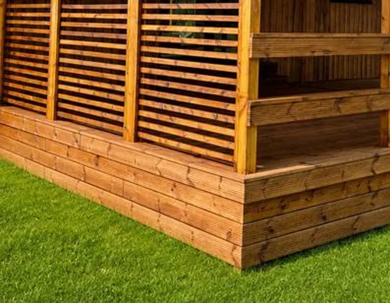 Moderne Pergola aus Holz mit Lamellen-Sichtschutz an einer Terrasse von Compact Haus auf einer gepflegten Rasenfläche.