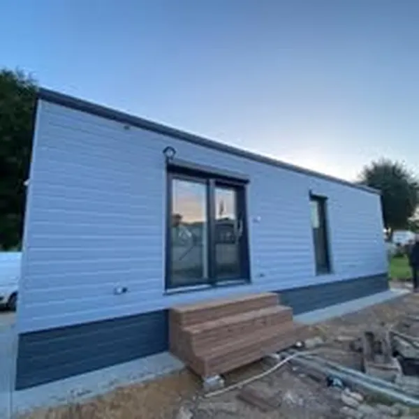 Modernes Mobilheim von Compact Haus mit Pultdach, großer Glasschiebetür und zweifarbiger Fassade in Grau und Anthrazit.