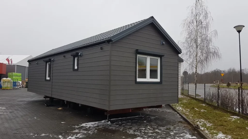 Winterfestes Mobilheim von Compact Haus mit grauer Fassade, Satteldach und mobilem Trailer-Fahrgestell.