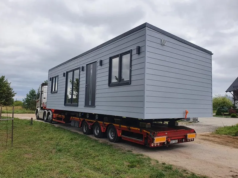 Professioneller Transport und schlüsselfertige Anlieferung eines modernen Flachdach-Mobilheims von Compact Haus.