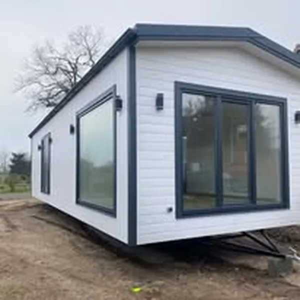 Mobiles Tiny House von Compact Haus in Weiß und Anthrazit mit großen Panoramafenstern und sichtbarem Trailer-Fahrgestell.