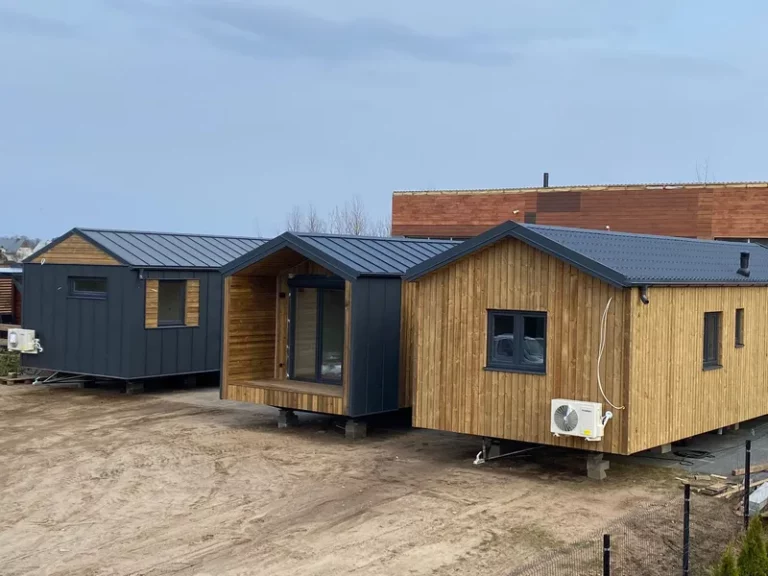 Mehrere winterfeste Mobilheime der MONO-Serie von Compact Haus mit Holzfassade, Klimaanlage, überdachter Terrasse und anthrazitfarbenem Satteldach auf einem Stellplatz.