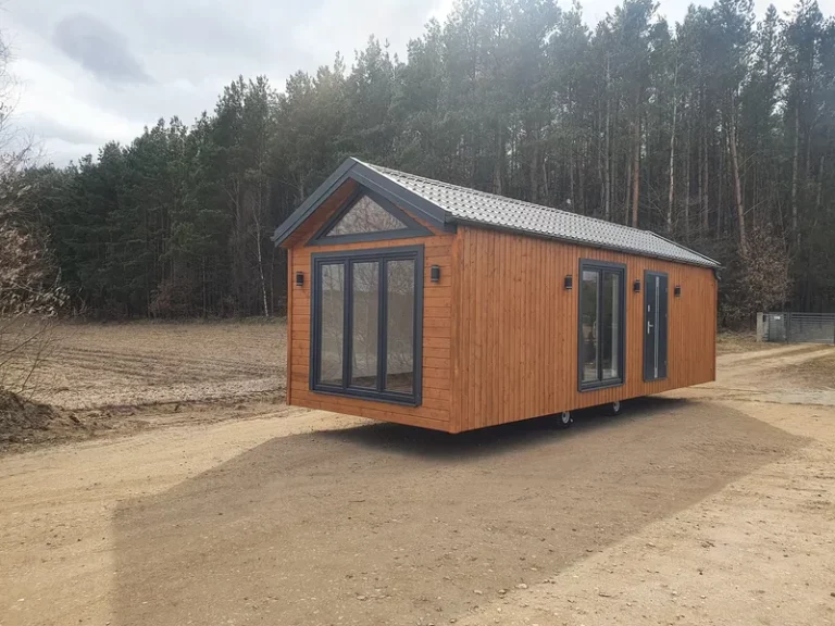 Mobiles Ganzjahres-Mobilheim von Compact Haus mit Satteldach, großen Giebelfenstern und natürlicher Holzfassade.