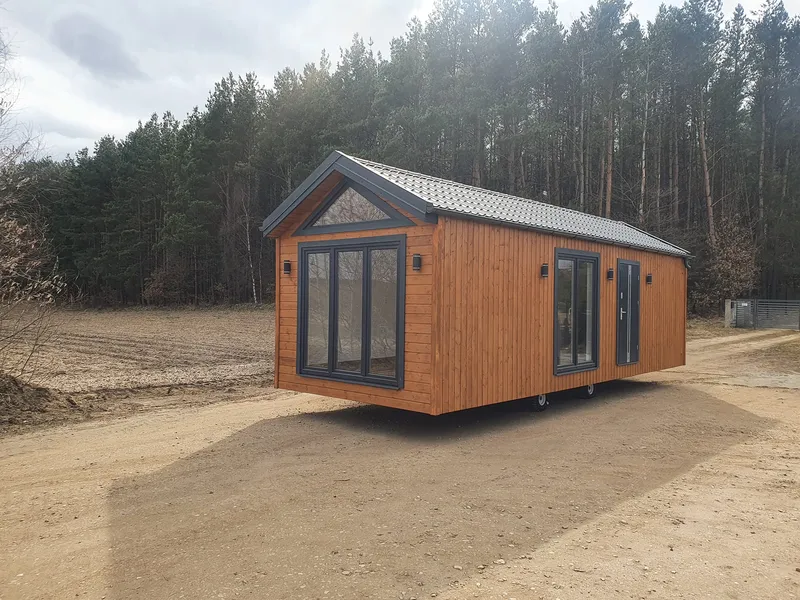 Mobiles Ganzjahres-Mobilheim von Compact Haus mit Satteldach, großen Giebelfenstern und natürlicher Holzfassade.