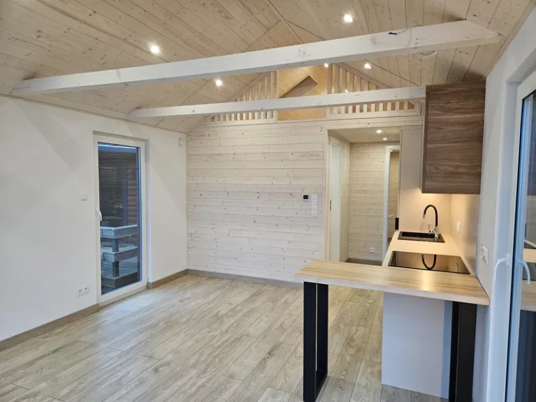Offener Wohn- und Kochbereich im skandinavischen Stil in einem Modulhaus der MONO-Serie von Compact Haus mit moderner Küche, Echtholzdecke und Empore.