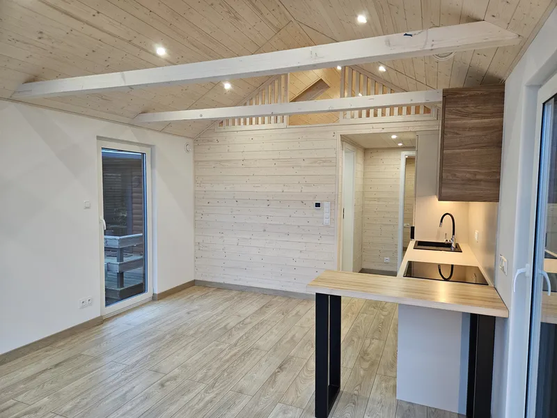 Offener Wohn- und Kochbereich im skandinavischen Stil in einem Modulhaus der MONO-Serie von Compact Haus mit moderner Küche, Echtholzdecke und Empore.