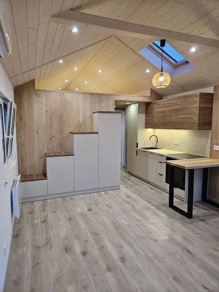Moderner Wohn- und Kochbereich im skandinavischen Loft-Stil in einem Modulhaus der MONO-Serie von Compact Haus mit Einbauküche, Dachfenster und maßgefertigtem Einbauschrank.