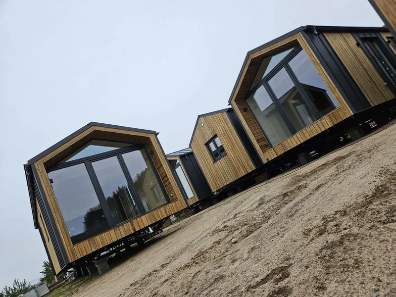 Winterfestes Modulhaus der MONO-Serie von Compact Haus in Holzständerbauweise mit großflächiger Glasfront, Holzfassade und anthrazitfarbenen Fassadenelementen.