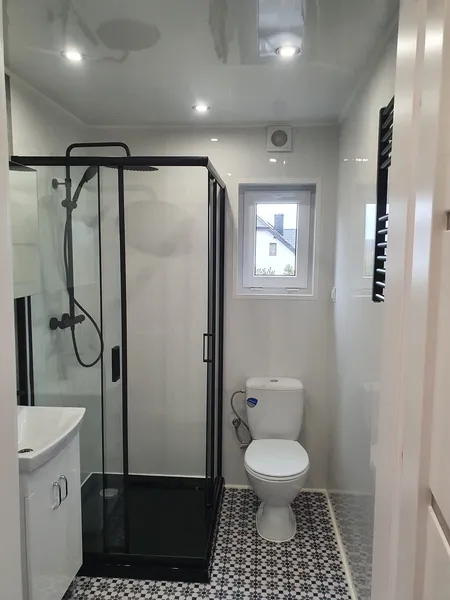 Modernes Badezimmer in einem winterfesten Tiny House der MONO-Serie von Compact Haus mit Mosaikboden, Glasdusche und mattschwarzen Armaturen.