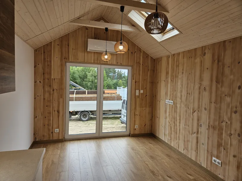 Gemütlicher Wohnbereich im modernen Loft-Stil in einem winterfesten Tiny House der MONO-Serie von Compact Haus mit Echtholzwänden, Dachfenster und Klimaanlage.