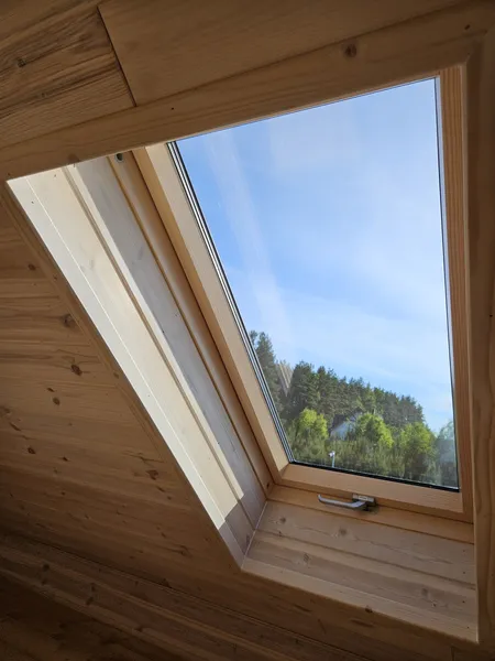 Detailaufnahme eines Dachfensters im Innenbereich eines winterfesten Tiny Houses der MONO-Serie von Compact Haus mit Echtholzverkleidung und Blick ins Grüne.