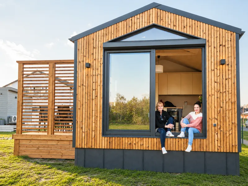 Das Team von Compact Haus im Panoramafenster eines modernen Mobilhauses im Unger Park Werder