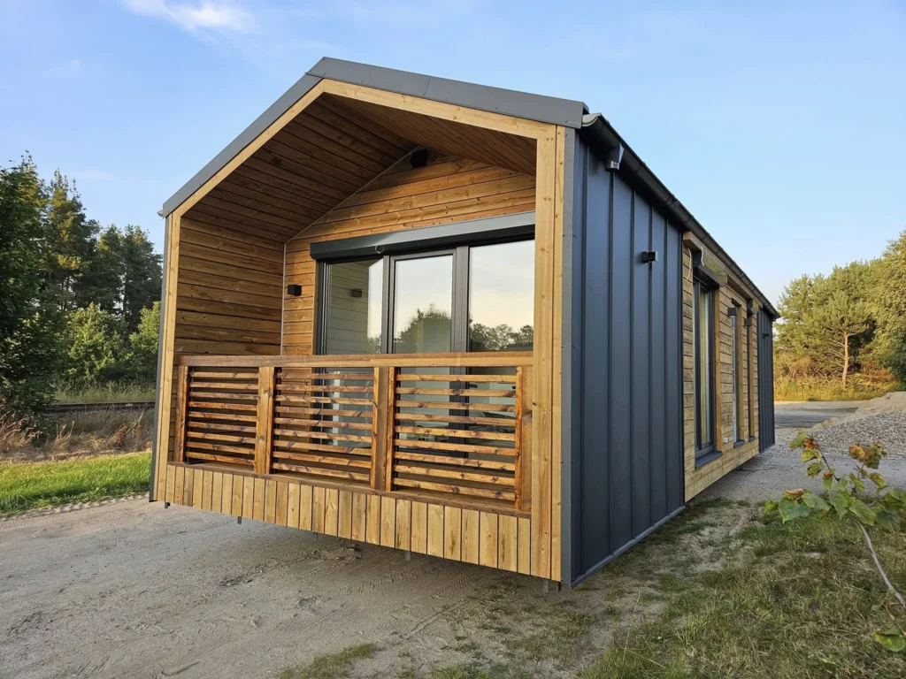 Modernes winterfestes Mobilheim der MONO-Serie von Compact Haus im skandinavischen Barnhouse-Stil mit anthrazitfarbenem Stehfalzblech und integriertem Holzbalkon.