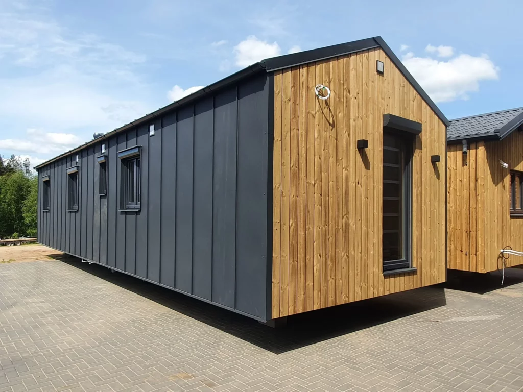 Seitenansicht eines Mobilheims im modernen Barnhouse-Stil der MONO-Serie von Compact Haus mit anthrazitfarbener Stehfalz-Fassade und vertikaler Holzverkleidung am Giebel.