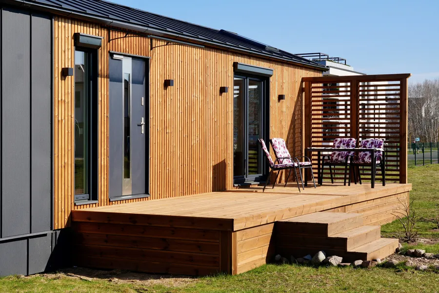 Moderne Holzterrasse und Außenfassade eines Compact Haus Mobilheims, das als ebenerdiger Bungalow genutzt wird